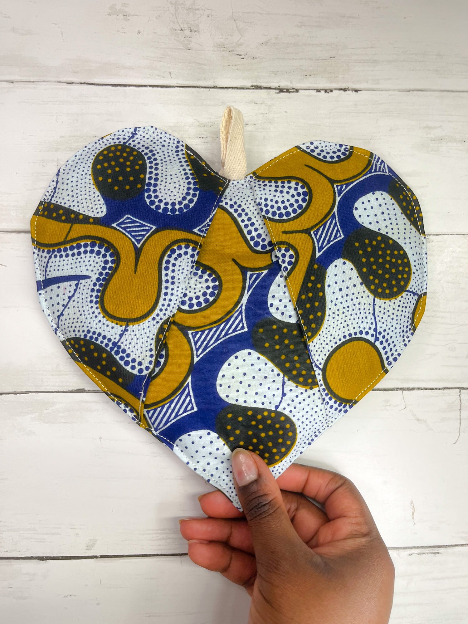 An intricately designed heart-shaped pot holder featuring vibrant African print patterns, perfect for adding a touch of cultural flair to your kitchen decor while providing functional heat protection.